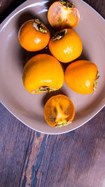 Persimmon cut into halves on a plate on a wooden table,copy space,closeup