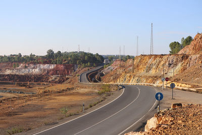 Road leading towards city against clear sky