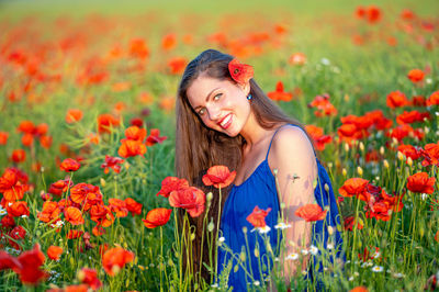 Portrait of young woman amidst flowers blooming in field