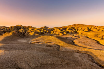 Scenic view of arid landscape against sky during sunset