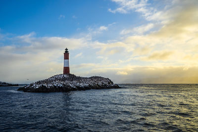 Lighthouse by sea against sky