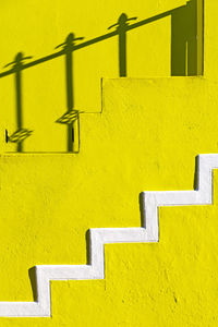Yellow steps against wall during sunny day