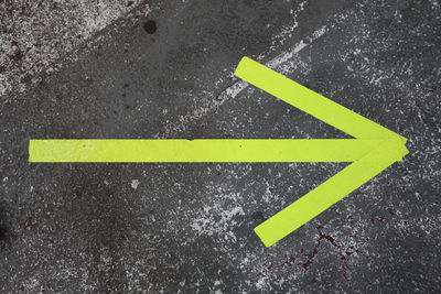 Close-up of arrow sign on road in city