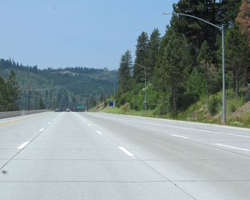 Road by trees against sky