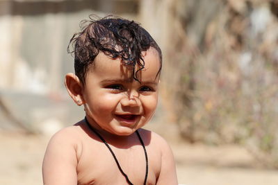  a small cute indian hindu child expresses happiness while taking a bath with unclothed