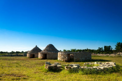 Built structure on field against blue sky