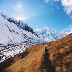 Rear view of man walking on snowcapped mountain