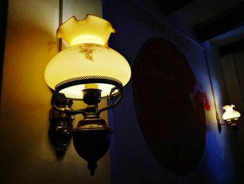 Low angle view of illuminated light bulb hanging at home