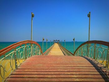 Bridge over sea against clear blue sky