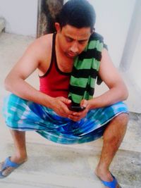 Midsection of man holding camera while sitting outdoors