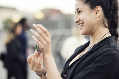 Side view of happy woman showing mobile phone