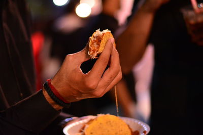 Close-up of hand holding taco at night