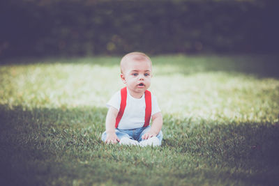 Cute boy sitting on grassy field