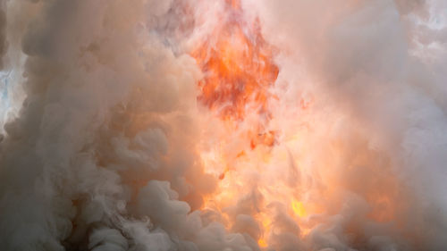 Low angle view of fire against clouds in sky