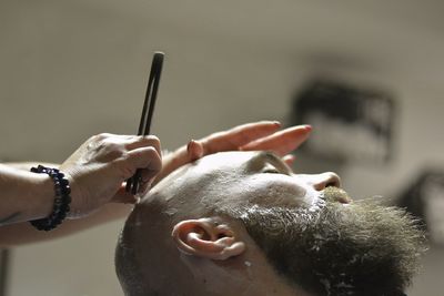 Cropped hands of barber shaving man at salon