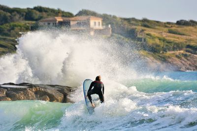 Rear view of man surfboarding in sea