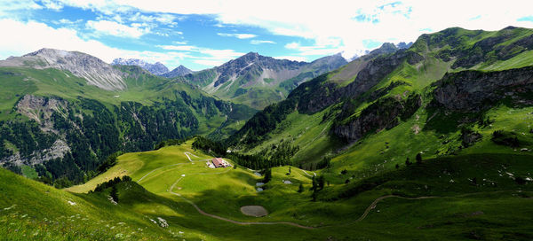 Scenic view of green landscape and mountains against sky