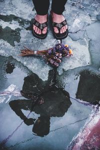 Low section of woman standing on puddle during rainy season