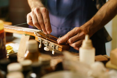 Midsection of man preparing guitar in workshop