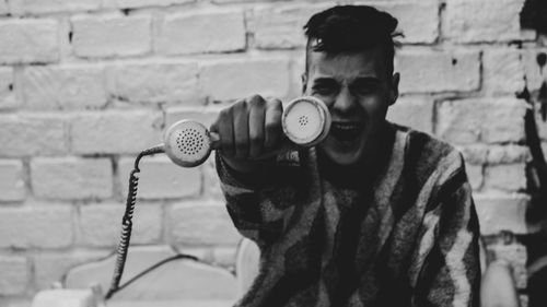 Portrait of young man standing against wall, acting