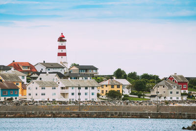 Buildings by river against sky