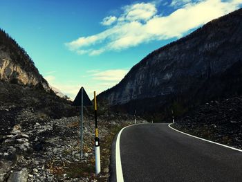 Empty road by mountains against sky