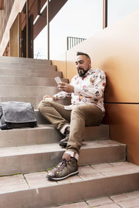 Handsome young man dressed casually spending time outdoors with mobile