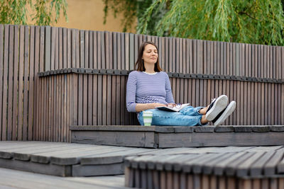 Woman reads a book and rests in a public place drinks coffee. a european woman meditates in the park