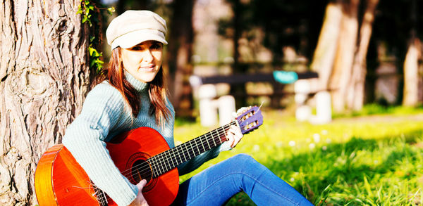 Portrait of woman playing guitar at park