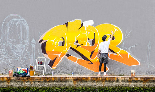 Rear view of man holding yellow umbrella