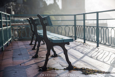 Empty bench on table by railing