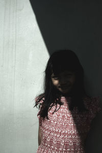 Young woman standing against wall