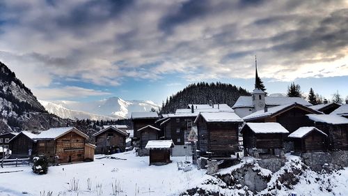 Houses on snow covered village against sky
