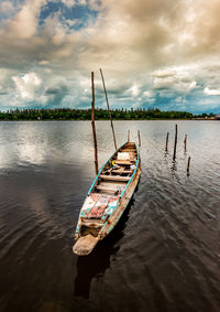 Wooden post in river against sky