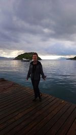 Full length of woman standing on pier over sea against sky