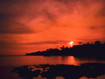 Scenic view of sea against dramatic sky during sunset