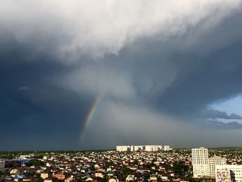 Rainbow over buildings in city against sky