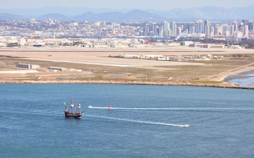 High angle view of people sailing on sea by cityscape against sky