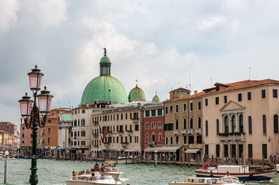 Boats in canal amidst buildings against sky