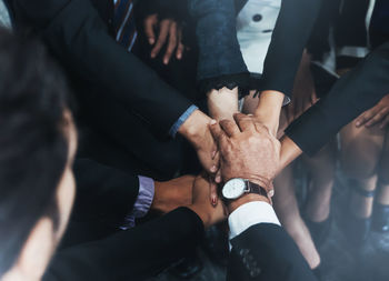 Midsection of friends stacking hands in office