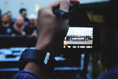 Cropped image of man photographing people on stage