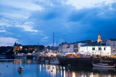 Sailboats moored at harbor against sky