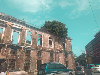 Cars on road by buildings against sky in city