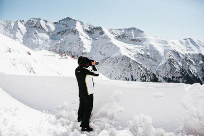 Man standing on snowcapped mountain against sky