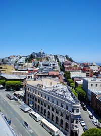 Distant view of coit tower in city against clear blue sky on sunny day