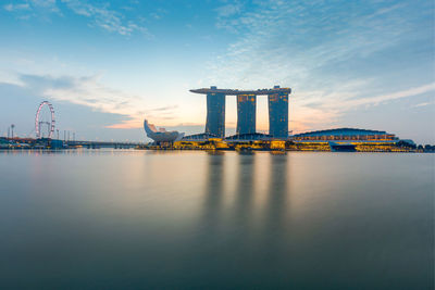 Marina bay sands in front of river against sky during sunset
