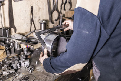 Midsection of worker measuring metal in factory