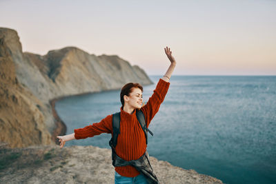 Full length of young woman standing by sea against sky