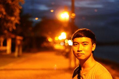 Portrait of young man against illuminated lights at night