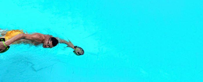 Man trains in pool. view from above on a ailetic male swimmer swimming in the blue clear water 